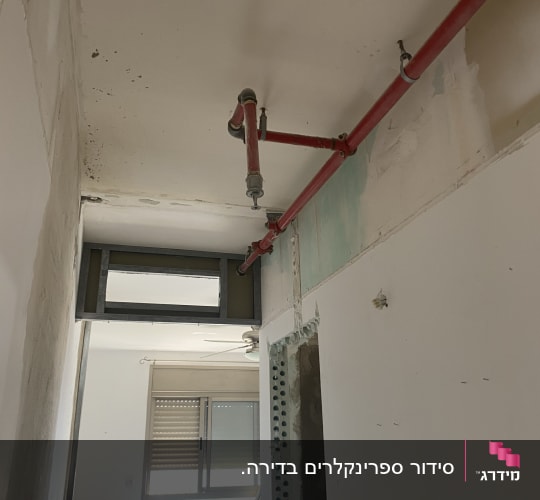 צינור כיבוי אש אדום מותקן על תקרה לבנה